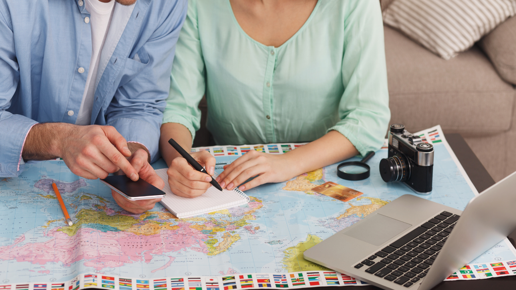Couple planning a trip with a map, laptop, and smartphone