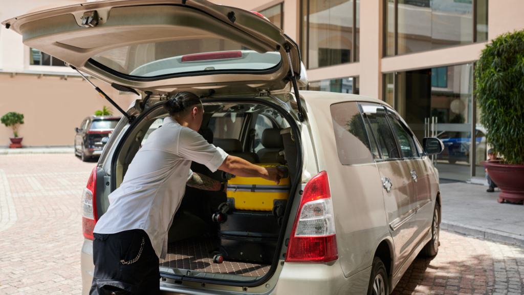 Driver loading travelers’ luggage into a transfer vehicle  